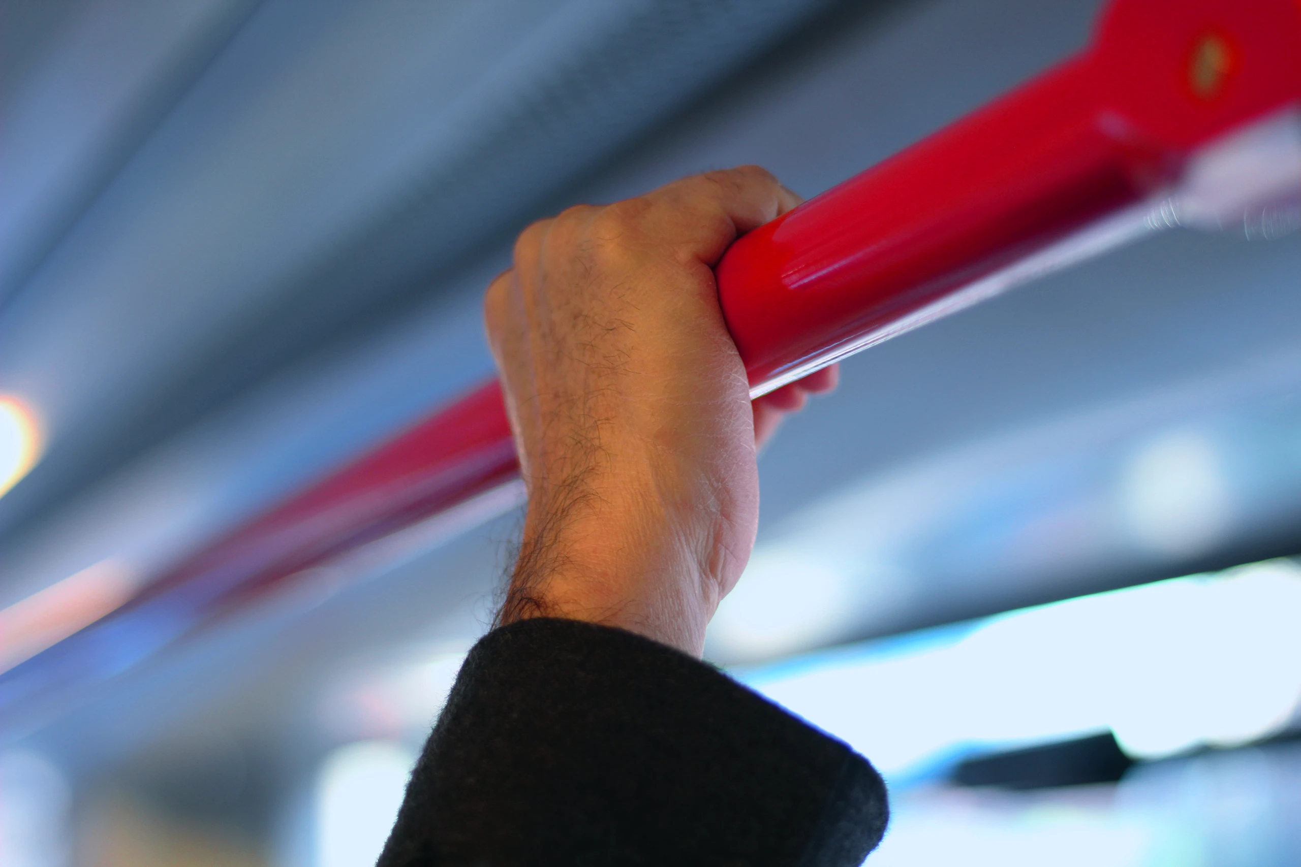 A close-up of a hand gripping a red overhead rail inside a train or public transport carriage, shallow depth of field, conveying movement and transit. PAGE: For C-Suite — identitytravel.com/solutions/for-c-suite/ Page focus keyword: corporate travel programme performance ALT TEXT (paste into: Media Library → Alt Text field) Close-up of a hand gripping a rail on a train, representing business travel in motion across a corporate travel programme