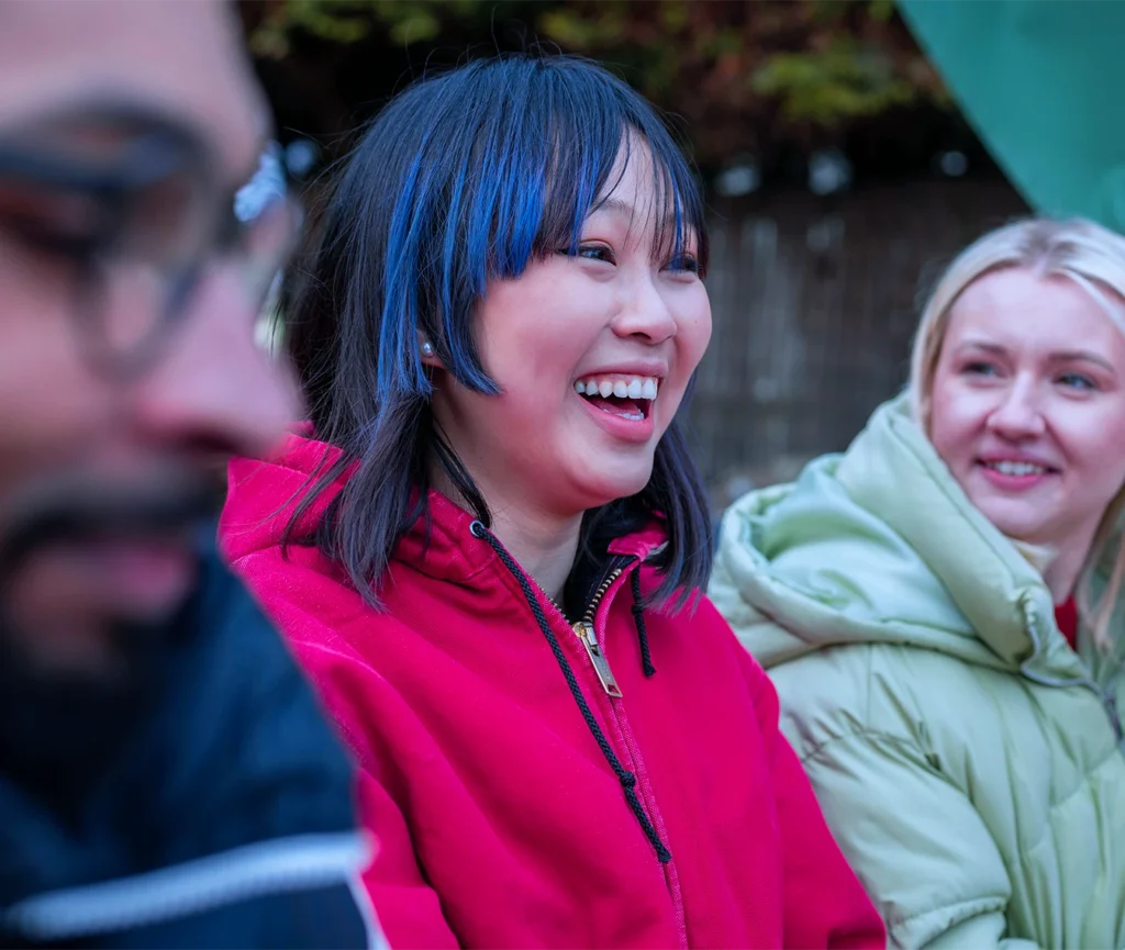 Alt text: A group of people smiling and engaged at an outdoor gathering, representing the human side of coordinated group travel management for business meetings and corporate events.
