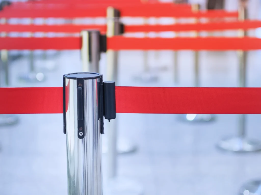 Queue barriers with red tape representing the risks of single-platform lock-in in corporate travel management technology decisions