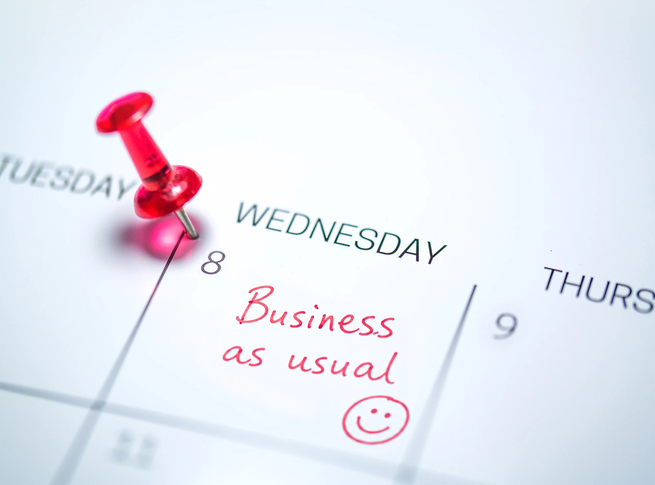 Calendar planner with 'Business as usual' handwritten in red on Wednesday and pinned with a red thumbtack, reflecting the routine nature of cross-border business travel on the island of Ireland